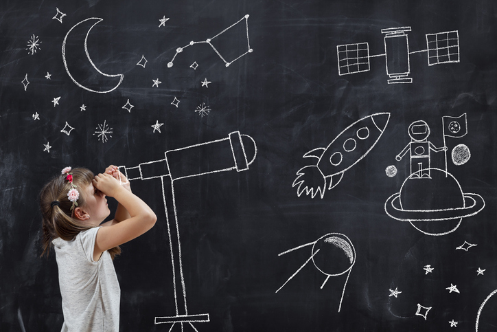 Abbildung zeigt Schülerin, die durch ein mit Kreide aufgezeichnetes Fernrohr blickt. Im Hintergrund sind aufgezeichnete Symbole der Raumfahrt zu erkennen.