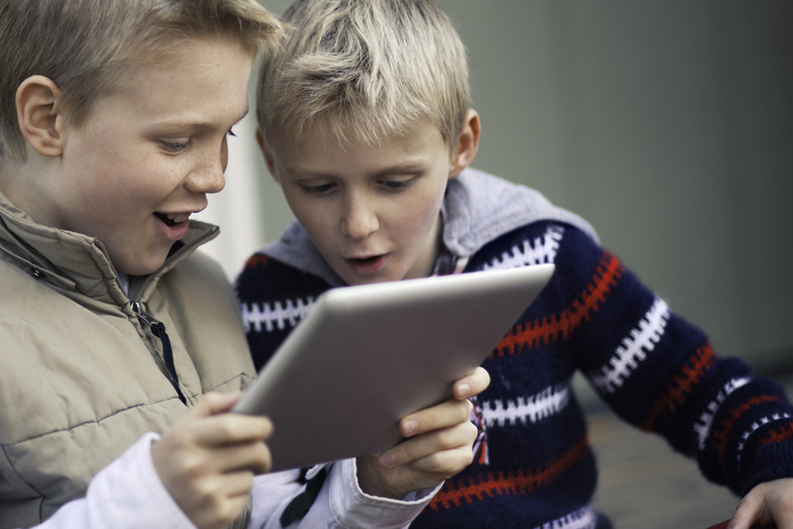 Abbildung zeigt zwei Schüler, die gemeinsam Inhalte auf einem Tablet betrachten.